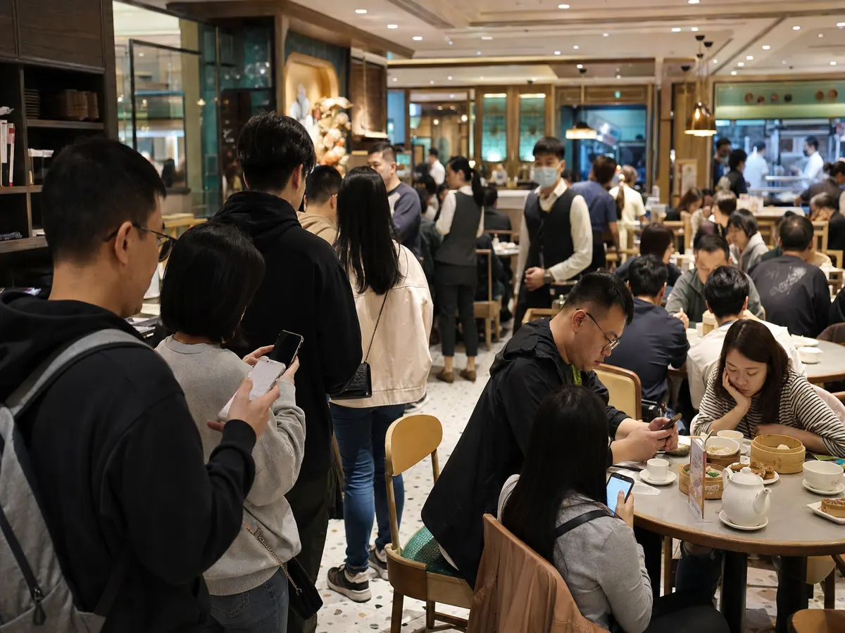 客人喺餐廳用手機睇籌號，櫃檯叫號同顯示屏同步更新